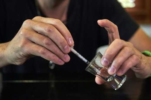 Steve Ludwin gathers snake venom with a syringe after extracting it from the reptile's fangs