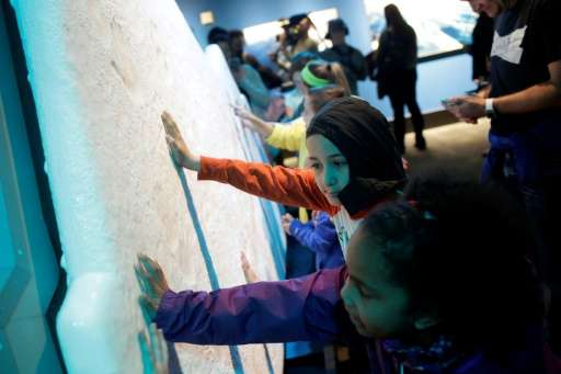Students on a field trip place their hands on a ice glacier replica  during the &quot;Extreme Ice&quot; exhibit at the Museum of