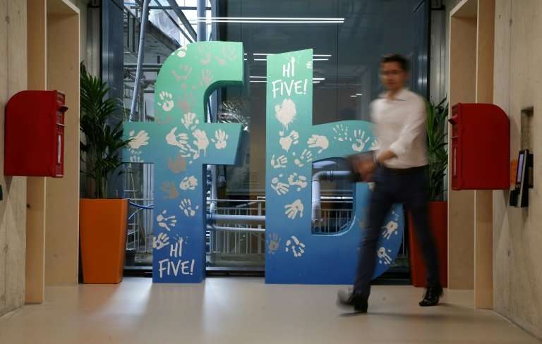 An employee walks past a Facebook logo at its new London headquarters
