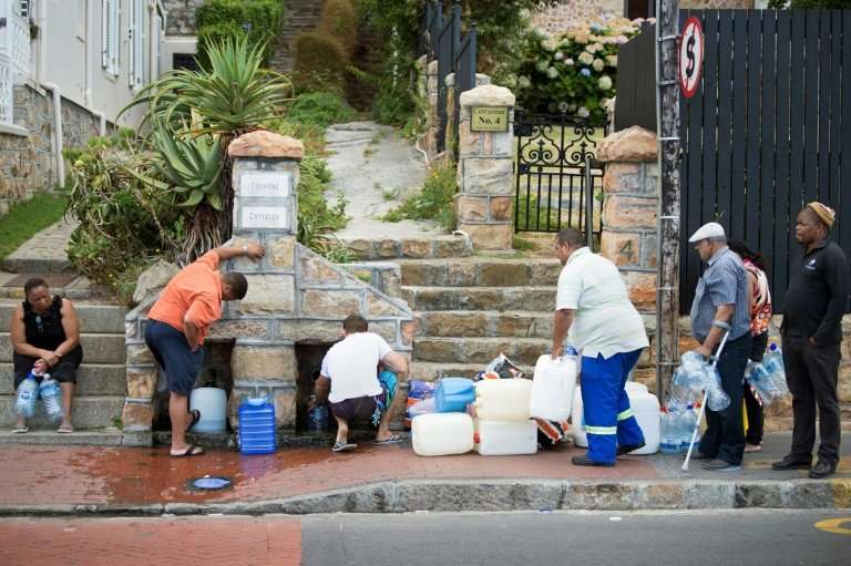 People collect drinking water from pipes fed by an underground spring