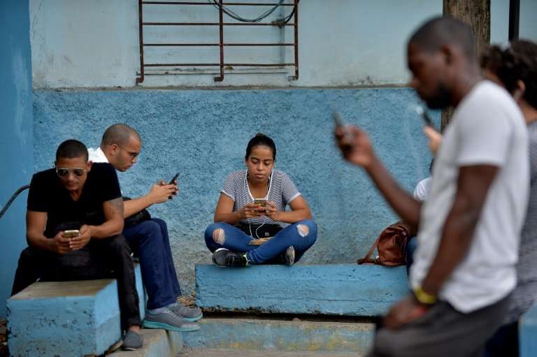 People use their mobile phones to connect to internet through WiFi at a park in Havana