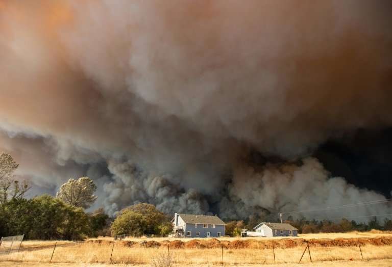 A home is overshadowed by towering smoke plumes on November 8, 2018 as the Camp fire races through town in Paradise, California