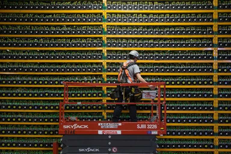 (FILES) In this file photo taken on March 19, 2018 A technician inspects the backside of bitcoin mining at Bitfarms in Saint Hya