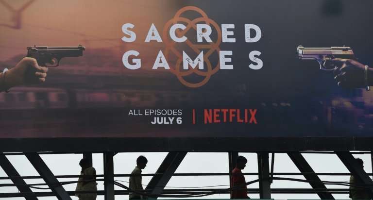 Indian commuters walk below a poster of &quot;Sacred Games&quot;, the Indian series on Netflix, in Mumbai