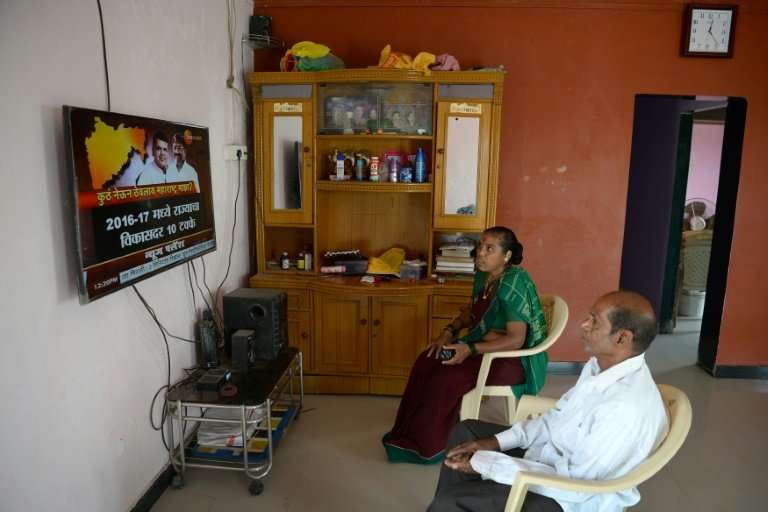 A couple watch television on Elephanta island near Mumbai, where hundreds of villagers have had mains electricity installed in t