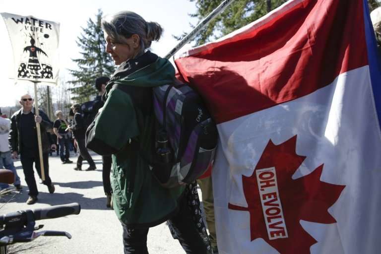 A demonstrator carrying a Canadian flag protests against the expansion of Texas-based Kinder Morgan's Trans Mountain pipeline pr