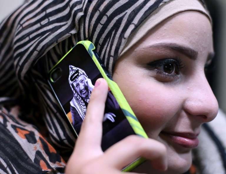 A file picture shows a young Palestinian woman using a mobile phone in the West Bank city of Ramallah on November 5, 2014