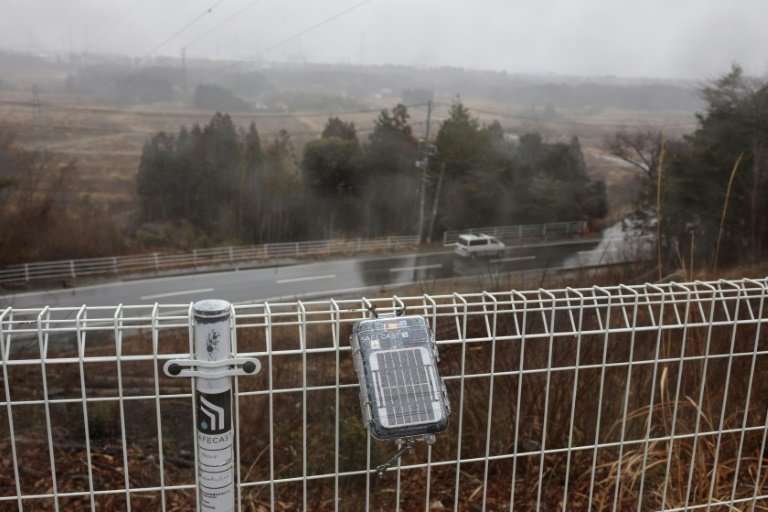 A geiger counter operated by the Safecast group is attached to a fence near the stricken Dai-ichi power plant