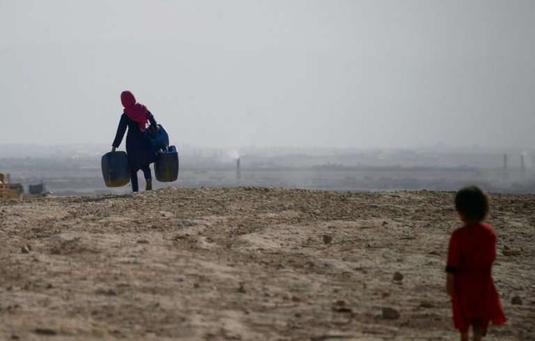 A girl carries containers to collect water on the outskirts of Mazar-i-Sharif in northern Afghanistan, where a lack of snow and 
