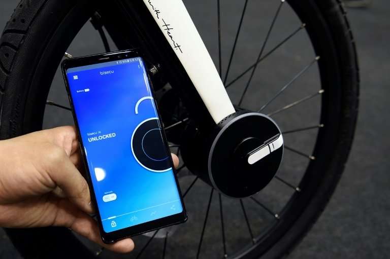 A host holds a mobile phone used to lock a Bisecu Smart Bike Lock on a bycicle at the Mobile World Congress (MWC), the world's b
