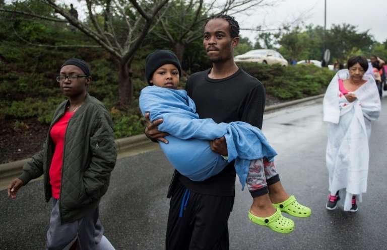 A man carries his son outside a Red Cross shelter near Raleigh, North Carolina, for people who fled Hurricane Florence