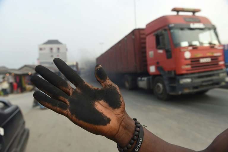 A man holds out his soot covered hand to illustrate how much soot covered the bonnet of his car in Port Harcourt