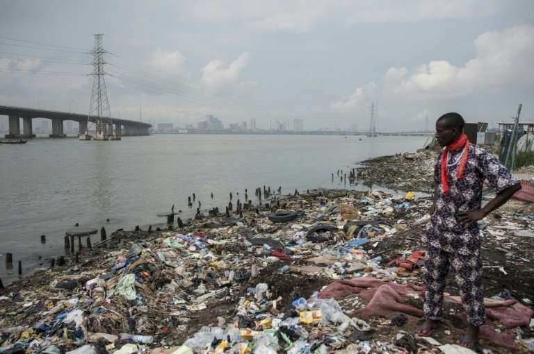 A man stands amid garbage near the sawmills area in Ebute Metta