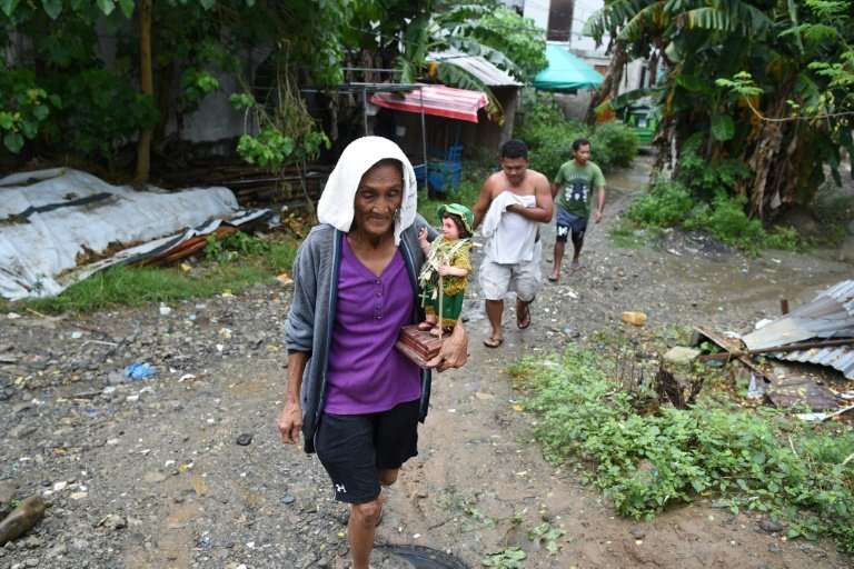 An elderly resident carries a religious icon as she evacuates to a safer place as Typhoon Mangkhut approaches the city of Tugueg