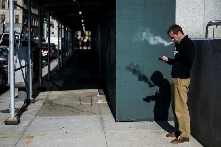 A New York man puffs away on his electronic cigarette. E-cigarettes may encourage youths to start smoking but may also help adul