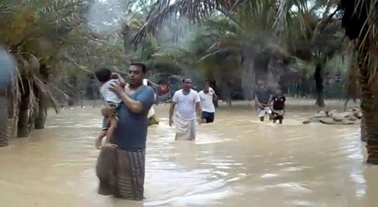 An image grab taken from an AFPTV video shows people walking through flood water as they evacuate a flooded area during a cyclon