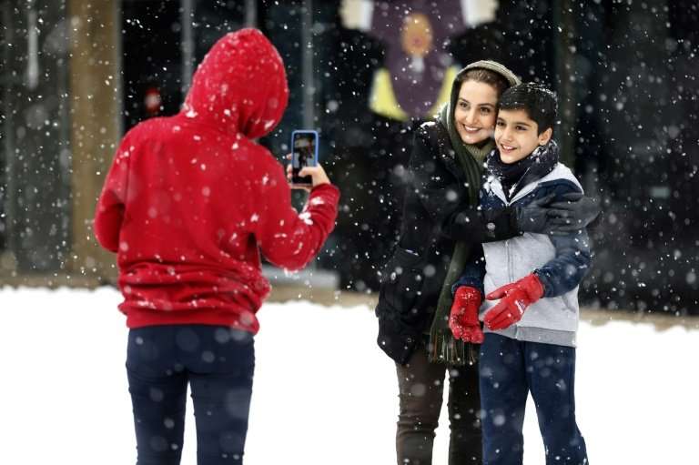 An Iranian woman and a child pose for a photograph during a snowstorm in the capital Tehran on January 28, 2018