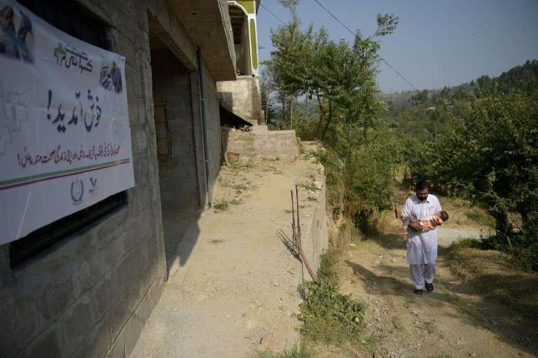 A Pakistani resident carries his sick son as they arrive at an online treatment clinic in the remote Bhosa village of Mansehra d
