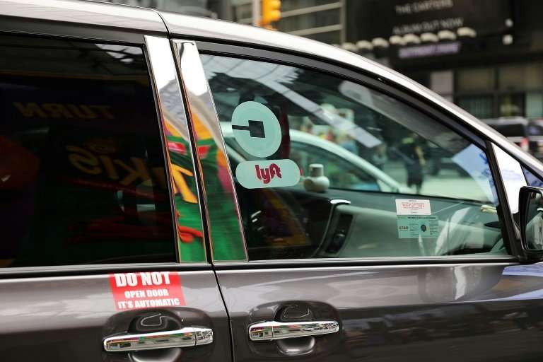 A ride hailing vehicle which has logos for both Lyft and Uber moves through traffic in Manhattan, amid intense competition betwe