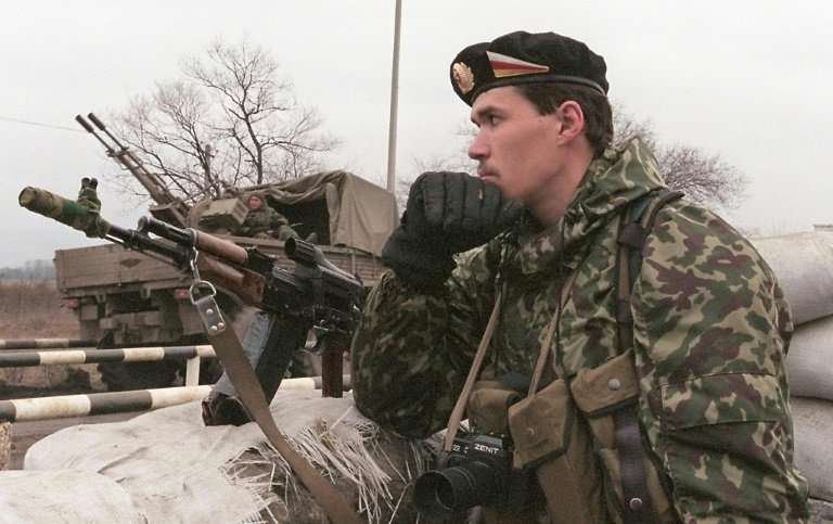 A Russian special police officer with a Zenit camera around his neck seen standing guard in February 2000 at a Chechen-Ingush bo
