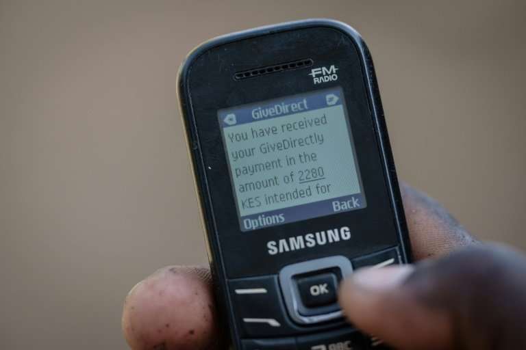A villager shows his mobile phone's monitor displaying a message confirming the universal basic income transaction, 2,250 shilli