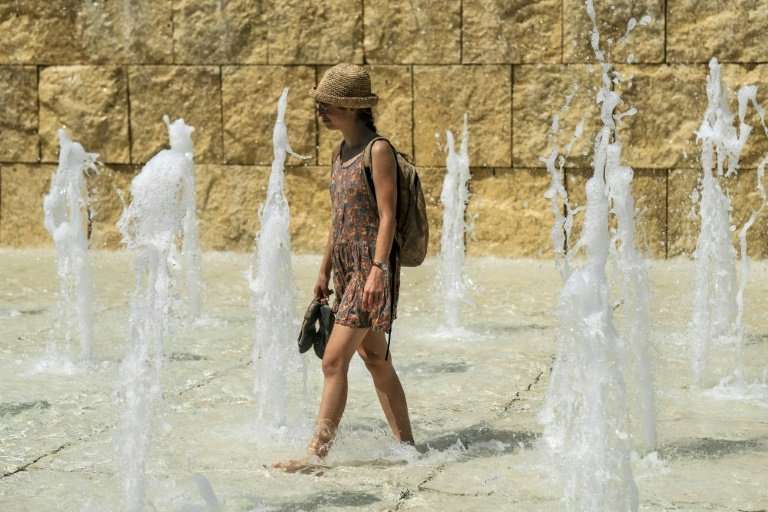 A woman cools herself in a fountain near the Ara Pacis monument in central Rome