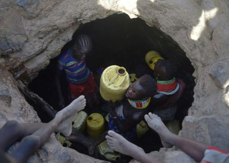 A young girl passes up a jerrycan filled with murky water from underground rocks in northern Kenya's Turkana county. A crippling