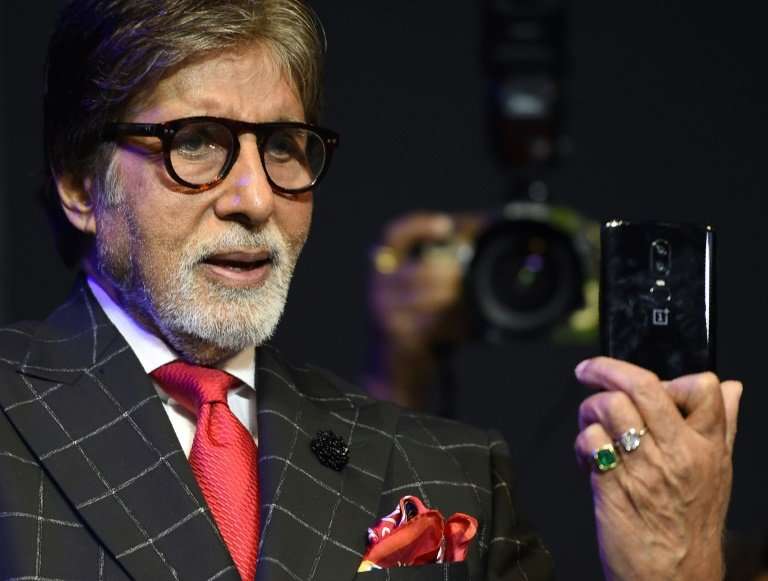Bollywood actor Amitabh Bachchan holds a mobile phone during a commercial event in Mumbai