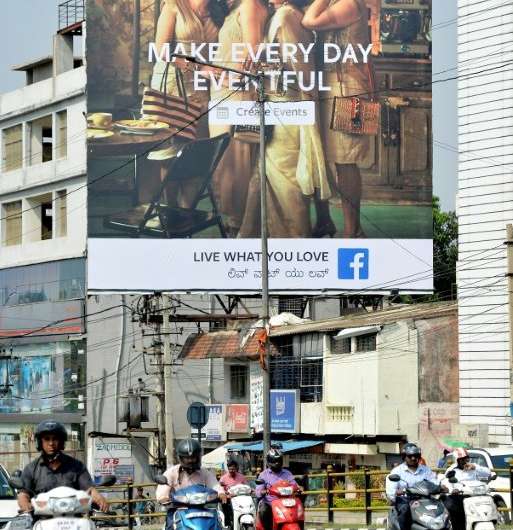 Indian commuters pass a poster advertising Facebook's 'Live What You Love' campaignaction for any attempt to influence polls by 