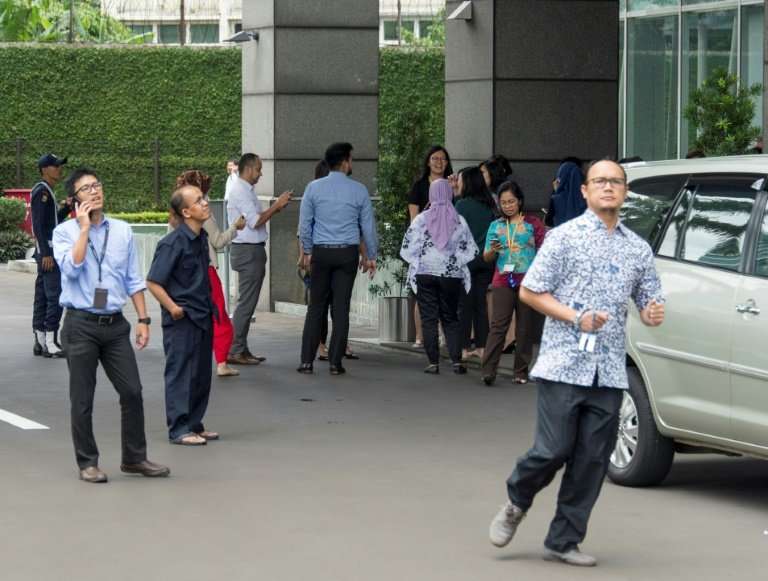 Indonesians stand outside office buildings after a strong quake hit Jakarta