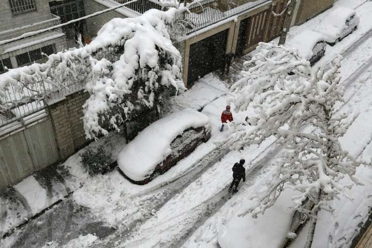 Iranians walk in the snow in the capital Tehran on January 28, 2018