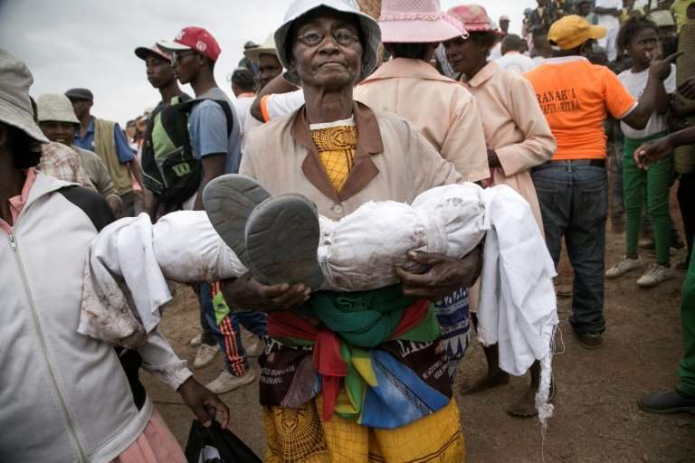 Isabel Malala Razafindrakoto carries the wrapped body of her son, who died aged just three years old, in the ritual of Famadihan