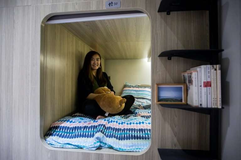 Michelle Chau sits on her bed in a co-sharing building in the Mong Kok district of Hong Kong, where spiralling housing prices ha