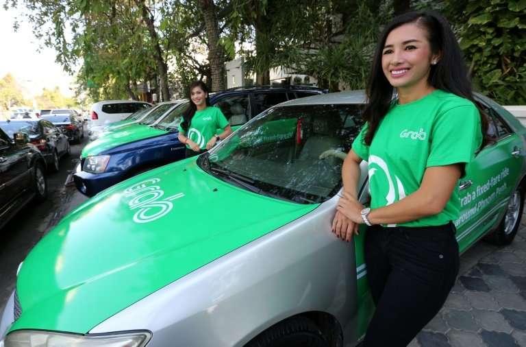 Models stand beside Grab cars in Phnom Penh during the ride hailing-firm's launch in Cambodia in December 2017