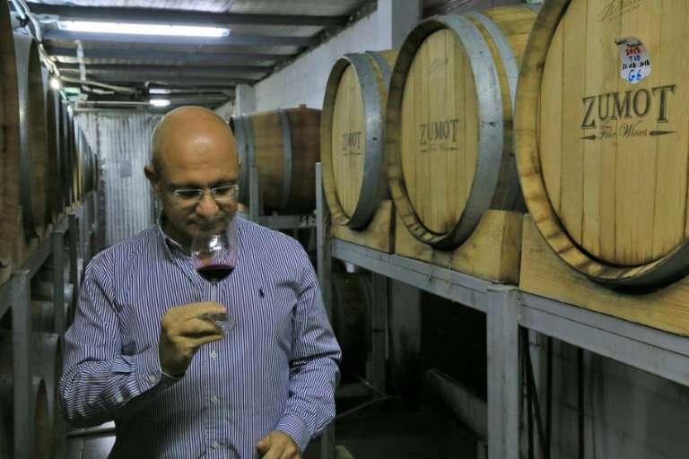 Omar Zumot, manager of Amman's Saint George winery and who studied winemaking in France, samples a glass as two Jordanian famili