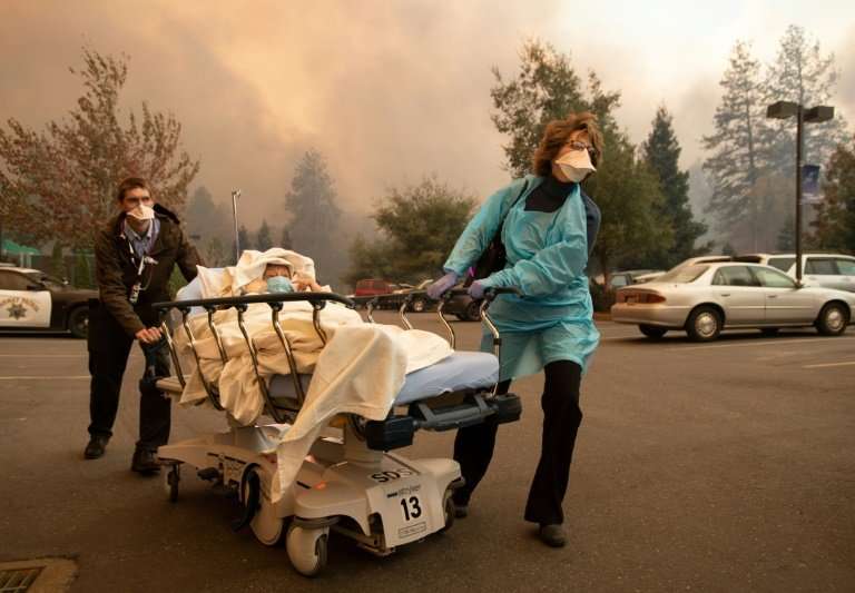 Patients are quickly evacuated from the Feather River Hospital as it burns down during the Camp fire in Paradise, California on 