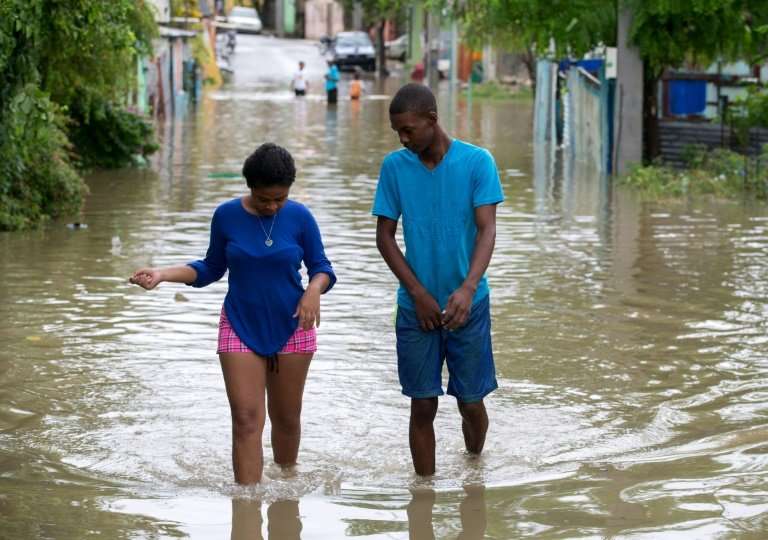 People wade through water in the flooded Moscu neighbourhood, in San Cristobal, Dominican Republic, after heavy downpours from t