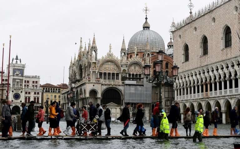 People walk on footbridges in flooded St Mark's Square during a high-water (Acqua Alta) alert in Venice