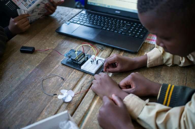 Pupils at the coding club in Ivory Park take wires from the breadboard—the base for building an electronics circuit—to a fan tha