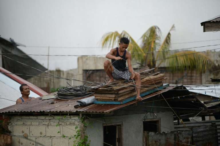 Residents secure the roof of their house as Typhoon Mangkhut approaches the city of Tuguegarao, Philippines