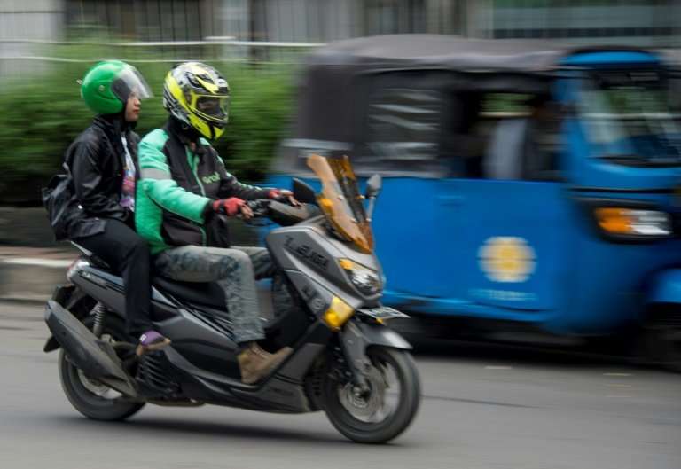 Ride-hailing apps like the Grab motorcyle-taxi seen here are denting the fortunes of traditional three-wheeled bajaj taxis in In