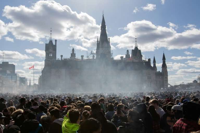 Smoke lingers over Parliament Hill in Ottawa as people smoke marijuana during Canada's annual 4/20 rally in April 2018, six mont