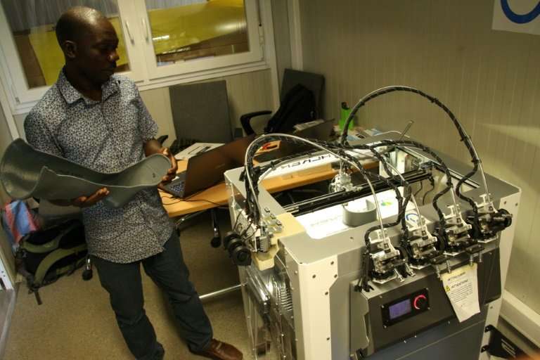 Technician Fabrice Agbelehounko Djodji checks the work of a 3D printer used to produce prosthetic supports at the African Organi