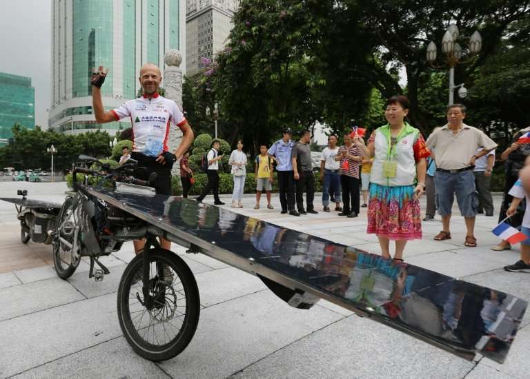 The bike is equipped with two solar panels—one in the front and another on a trailer behind