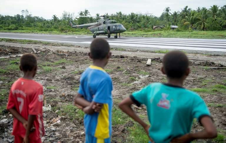 Three Papuan boys watch an Indonesian military Mi17 helicopter at Erwer airport in Agats, Asmat district, in West Papua