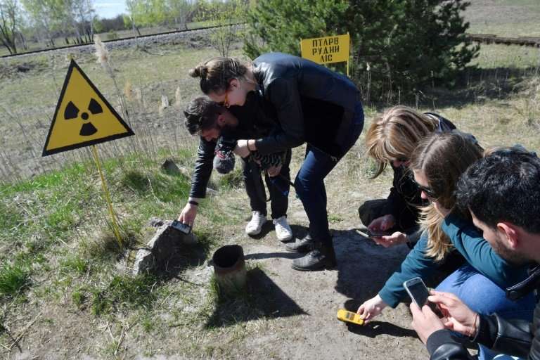 Tourists use Geiger counters to measure the level of radioactivity in the area