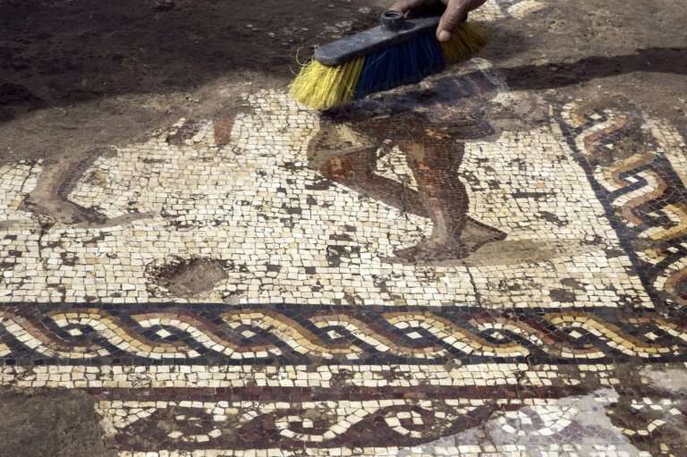Workers from the Israeli Antiquity Authority clean a rare Roman-era mosaic on February 8, 2018 north of Tel Aviv which archaeolo