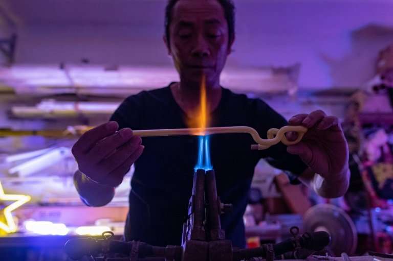 Wu Chi-kai bends glass tubes dusted inside with fluorescent powder into shape over a powerful gas burner