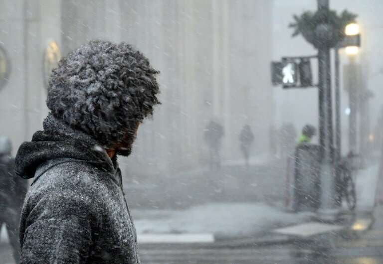 A man waits to cross a street in downtown Manhattan during a snow storm