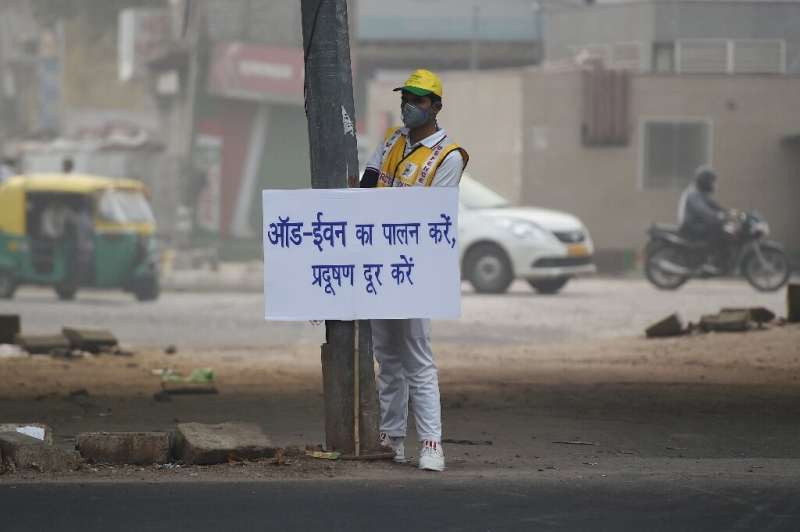 A volunteer in smog-choked New Delhi displays a placard warning drivers of the new odd-even number plate system in effect that s